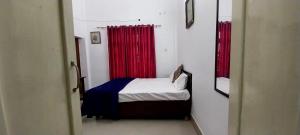 um pequeno quarto com uma cama com cortinas vermelhas em BAGEECHA VILLA em Allahabad