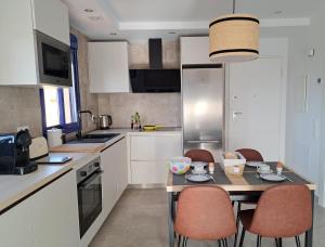 een keuken met witte kasten en een tafel met stoelen bij roomwithview casa marco in Mojácar
