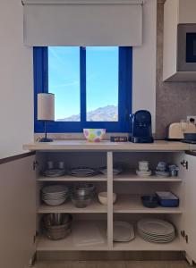 een keuken met een plank met borden en een raam bij roomwithview casa marco in Mojácar