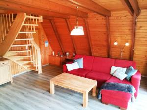 sala de estar con sofá rojo y escalera de madera en Ferienhaus Seestern, en Carolinensiel