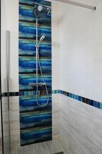 eine Dusche im Bad mit einer bunten Kachelwand in der Unterkunft M Art Inn Apartman in Soltvadkert