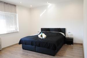 ein Schlafzimmer mit einem schwarzen Bett in einem weißen Zimmer in der Unterkunft M Art Inn Apartman in Soltvadkert