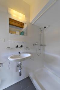 ein weißes Bad mit einem Waschbecken und einer Dusche in der Unterkunft Attic Chesa Charots - Celerina in Celerina