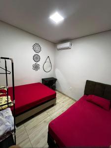 a bedroom with two beds and a red bedspread at JOTA Área de Lazer in Dourados