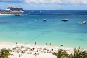 a beach with a cruise ship in the water at Holland House Beach Hotel in Philipsburg