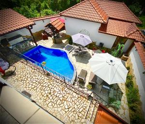 an overhead view of a swimming pool with two umbrellas at Къща за гости Casa Per Te село Огняново - село Марчево in Marchevo