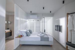 Beachfront Salty Sea Luxury Suite 1 في آغيوس نيكولاوس: غرفة نوم بيضاء فيها سرير وتلفزيون