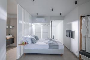 a white bedroom with a bed and a television at Beachfront Salty Sea Luxury Suite 1 in Agios Nikolaos
