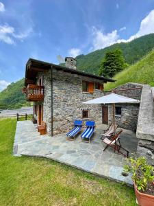 una casa y un patio con sillas y sombrilla en Chalet Dolce Vita, en Gerola Alta
