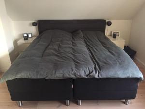 a bed with a gray comforter in a bedroom at Wonderful house & garden in Tommerup