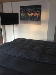 a bedroom with a black bed and a painting on the wall at Wonderful house & garden in Tommerup