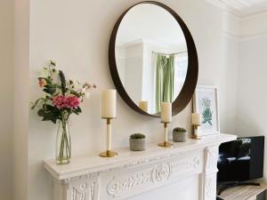a mirror on a mantle with candles and flowers at Briar Bank in Shanklin