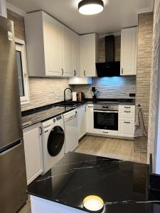 una cucina con mobili bianchi e un piano di lavoro nero di Casa Domenico ad Alicante