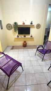 sala de estar con 2 sillas de color púrpura y TV en Casa praiana - agradável e confortável ambiente com ar-condicionado, en Parnaíba
