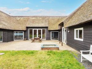 a house with a thatched roof and a patio at 20 person holiday home in R m in Toftum