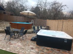 a hot tub in a backyard with a table and chairs at Балтовата къща in Medven