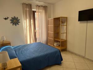 Un dormitorio con una cama azul y un televisor. en Casa Maruzzella, en Lipari