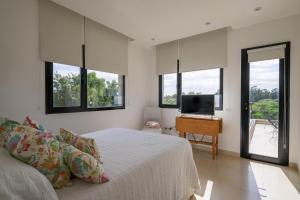 a bedroom with a bed and a desk and windows at Casa EL ORIGEN in Tandil