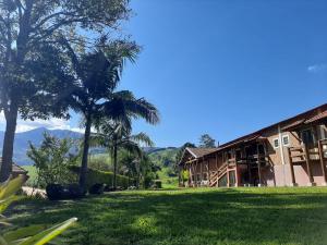 a house with palm trees in front of a yard at Pousada Pedra da Mina in Passa Quatro