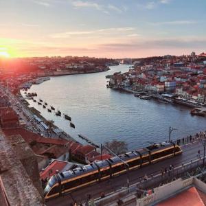 ein Zug an einem Bahnhof neben einem Fluss in der Unterkunft Fervença Apartments in Vila Nova de Gaia