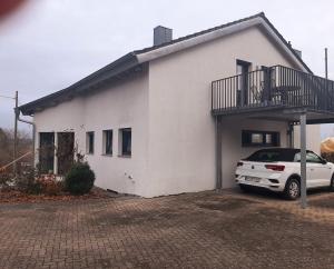 a white house with a car parked in front of it at FeWoHerrmann in Gundelsheim