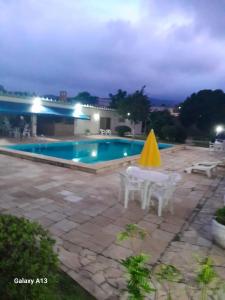 a pool with two tables and a yellow umbrella at Elysian Place in Atibaia