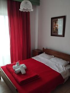 a bed with a teddy bear sitting on a red blanket at Pension Olympus in Litochoro