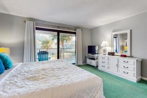 a bedroom with a bed and a window with a balcony at Seawinds Oceanfront Condo in St. Augustine