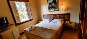 1 dormitorio con 1 cama grande y 2 ventanas en Villa D'Ouro Pousada, en Tiradentes