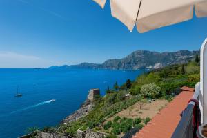 einen Blick auf das Wasser vom Balkon mit Sonnenschirm in der Unterkunft CASA OLGA, UN AFFACCIO SUL MARE !! in Praiano