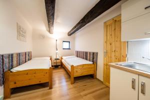 a room with two beds and a kitchen with a sink at Penzion Pod hradem in Adršpach
