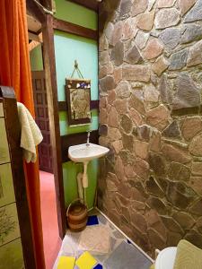 a bathroom with a sink and a stone wall at Cocoa Cottage in Roseau