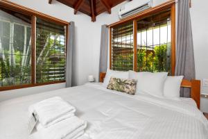 a bedroom with a large white bed with windows at Hotel Bahia Esmeralda in Potrero