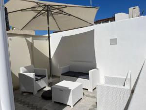 un patio con sillas blancas y una sombrilla en Casa Maruzzella, en Lipari