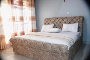 a bed with a tufted headboard in a room with windows at Zeyman’s Appartments in Kigali