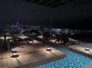 a rooftop pool at night with chairs and lights at Ekocheras Cozy Loft in Kuala Lumpur