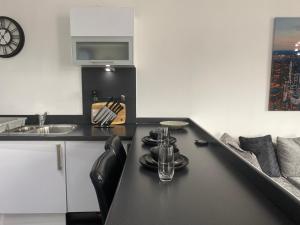 uma cozinha com um balcão preto e um lavatório em Luxury Apartment with Balcony em Dewsbury
