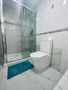 La salle de bains blanche est pourvue d'une douche et de toilettes. dans l'établissement Entire Queens Apartment Close to Hyde Park, Queensway, Bayswater, à Londres