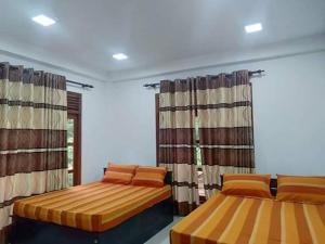two beds in a room with curtains at Stream Home in Haputale