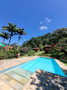 una piscina en un patio con palmeras en Sítio Canto a Canto, en Miguel Pereira
