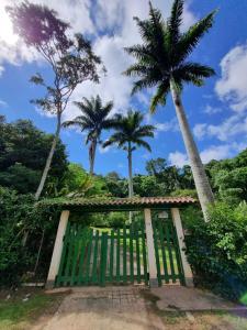 a green gate with palm trees in the background at Sítio Canto a Canto in Miguel Pereira