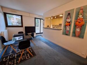ein Wohnzimmer mit einem Schreibtisch und Stühlen sowie eine Küche in der Unterkunft Superbe appartement terrasse in Levallois-Perret