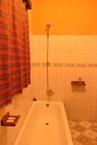 a bath tub in a bathroom with a red shower curtain at Room in BB - Amahoro Guest House - Queen Room in Ruhengeri