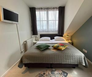 a bedroom with a bed with pillows and a television at Bed & Brasserie Het Kosthuys in Sint Maartensdijk