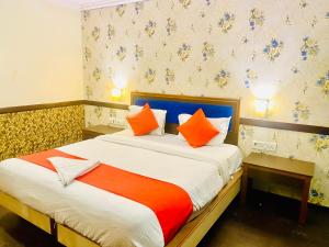Schlafzimmer mit einem Bett mit orangefarbenen und weißen Kissen in der Unterkunft The City Park hotel in Hyderabad