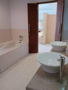 a bathroom with two sinks and a tub and a bath tub at Glisten Up Villa Beach Side Sanur! in Sanur