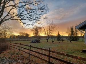 a fence in a field with a sunset in the background at Koekies Rum och Fika in Grillby