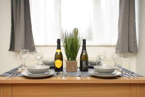 a table with two bottles of wine and glasses at Cosy One Bedroom Apartment in London