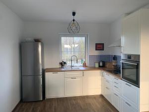 a kitchen with white cabinets and a stainless steel refrigerator at Żałesisko in Rypin