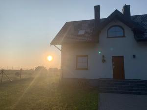 una casa bianca con il sole che tramonta dietro di essa di Żałesisko a Rypin